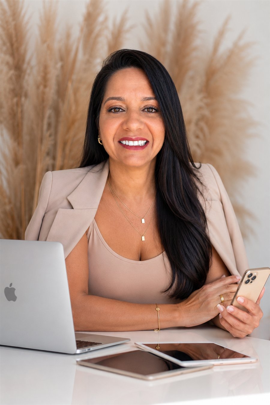 Janayna Melo sorrindo, sentada diante do notebook e do celular